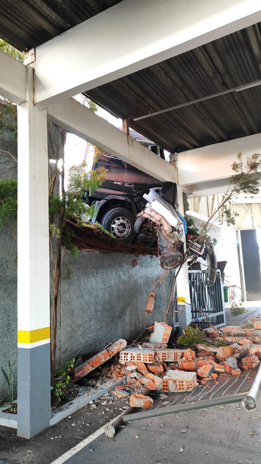 Veículo de carga desgovernado atinge veículo de passeio e pretendo o mesmo sobre edificação